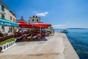 Enjoy a meal with a view of the sea from our outdoor dining area, featuring comfortable seating and shade from umbrellas.