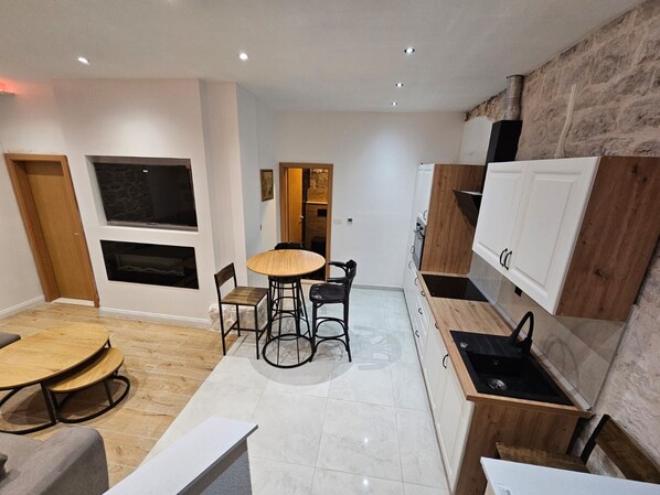 Modern kitchen and dining area with stove, round table, and four chairs.
