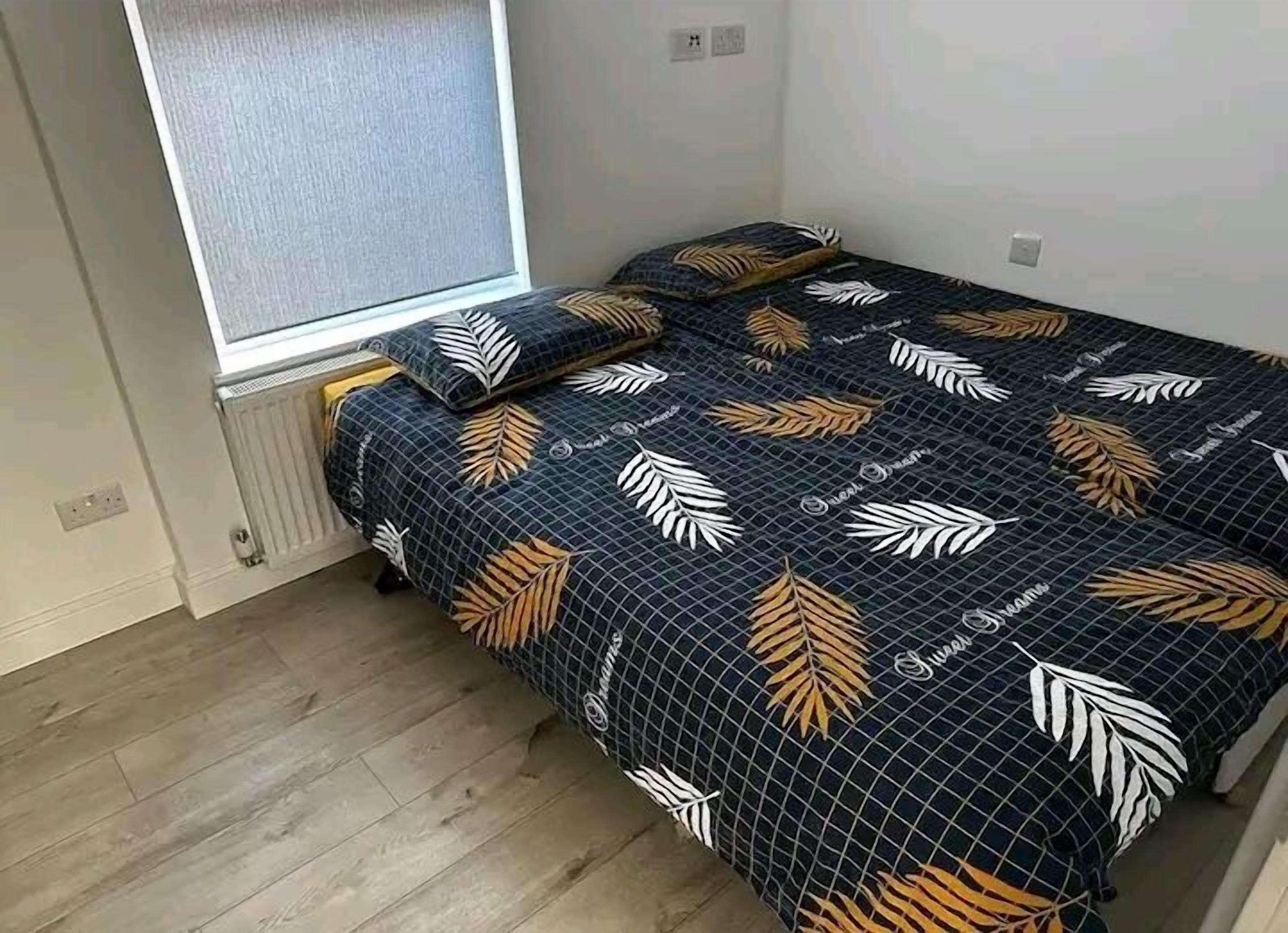 A small bedroom with a bed, a window, and a radiator.
