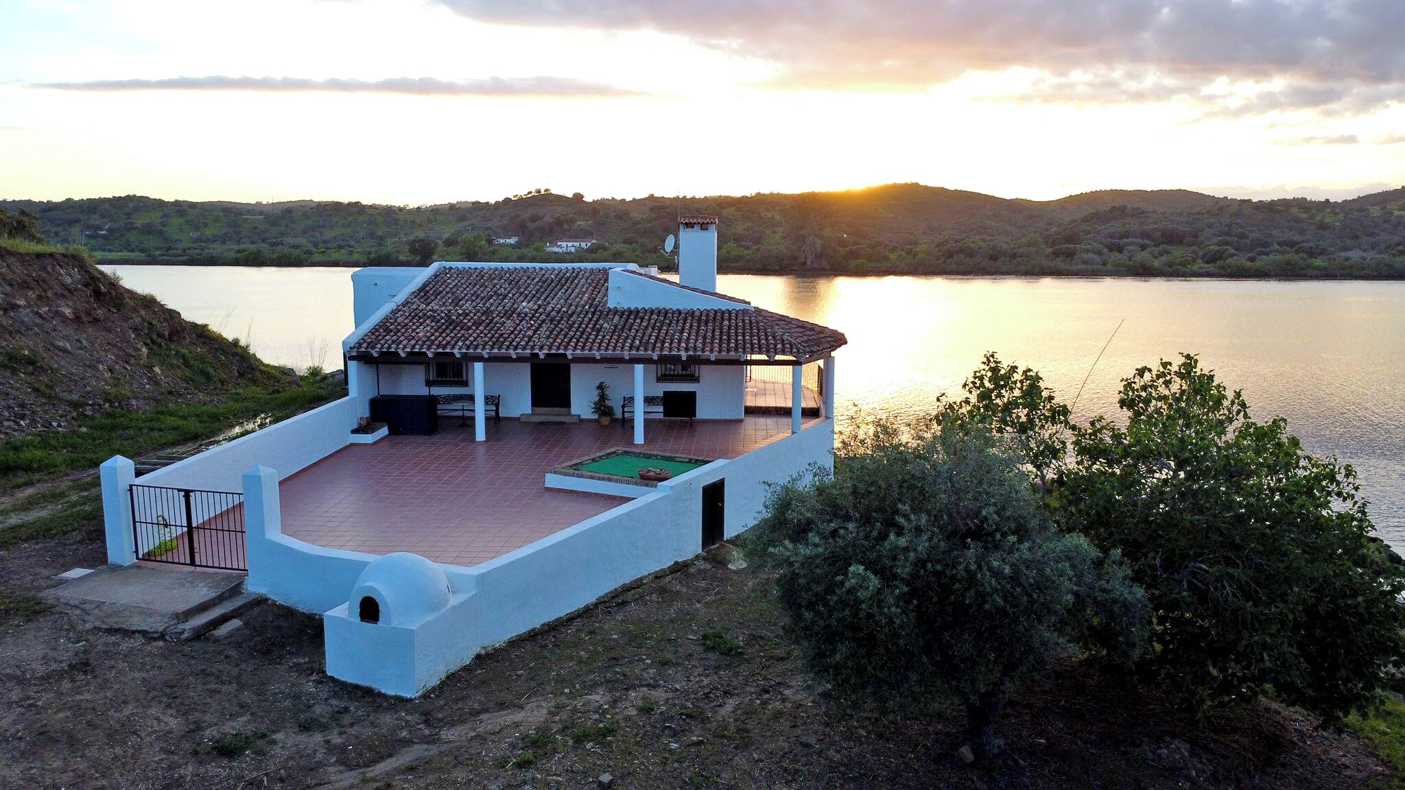 A coastal house with a tiled roof, a covered patio, and a view of the sea.