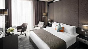 Una habitación de hotel moderna con una cama grande, un escritorio, una silla y un televisor.