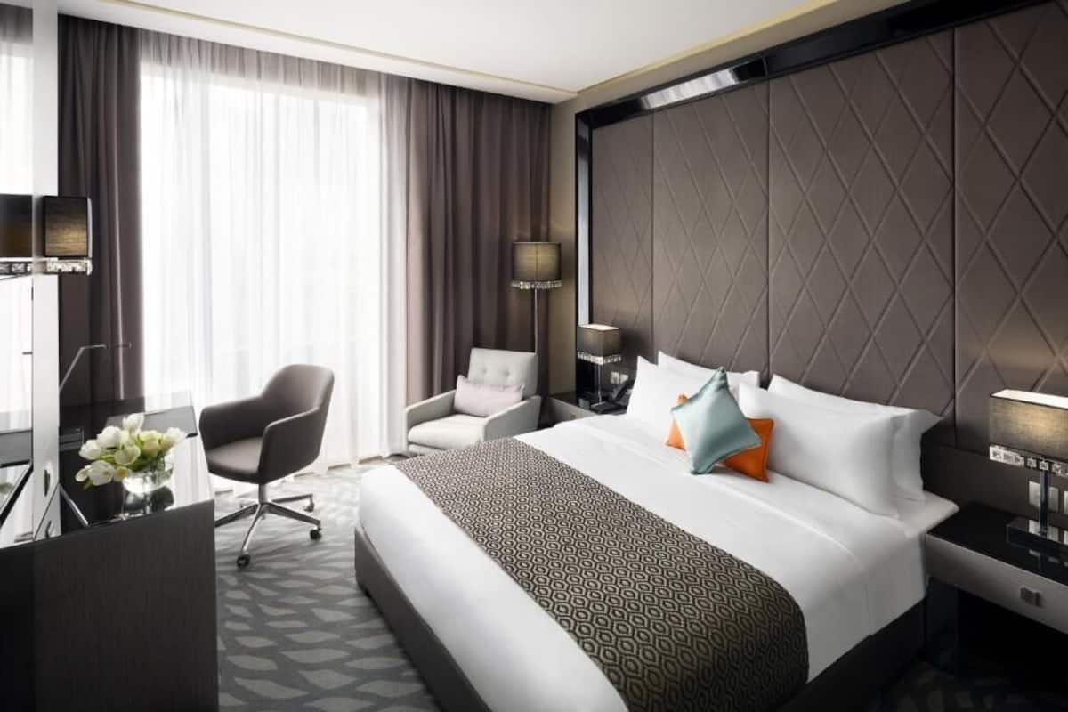 Una habitación de hotel moderna con una cama grande, un escritorio, una silla y un televisor.