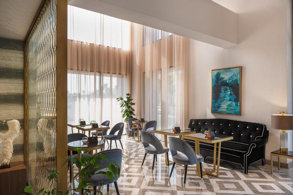A modern hotel room with a dining area, a sofa, and a painting on the wall.
