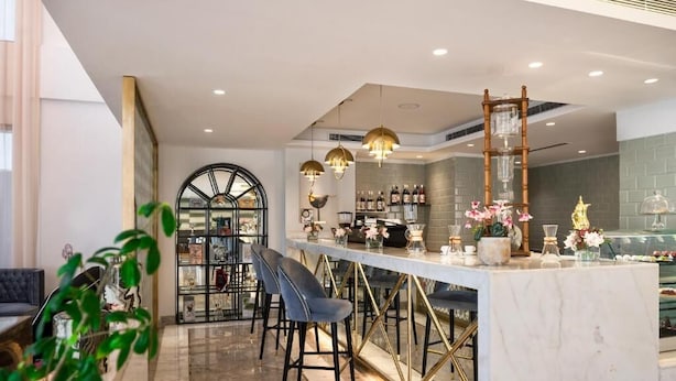 Zona de bar moderna con encimera de mármol, taburetes y luces decorativas.