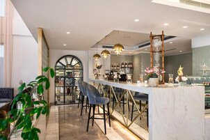 Zona de bar moderna con encimera de mármol, taburetes y luces decorativas.