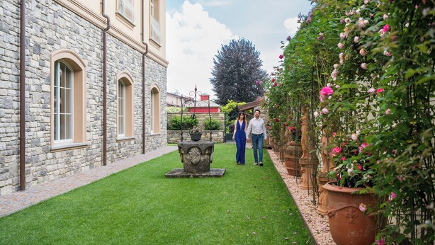 A stone building with arched windows and a well-maintained lawn. - Roof Suite - Castello il Codirosso Accomodation Hotel (Cesate)