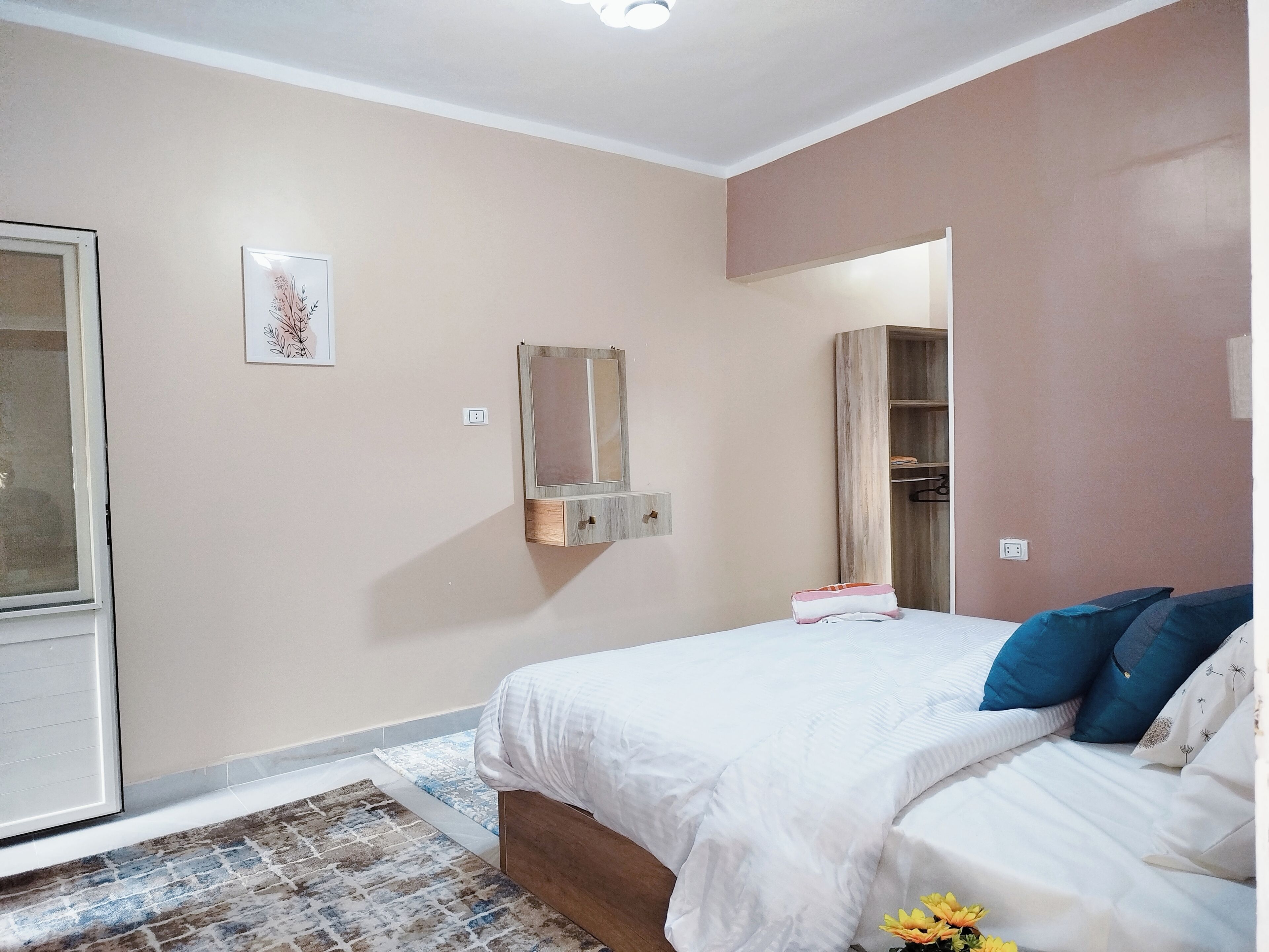 A bedroom with a bed, a wardrobe, a mirror, and a small bedside table.