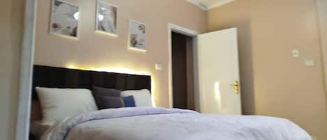 A bedroom with a bed, a headboard, and a door.