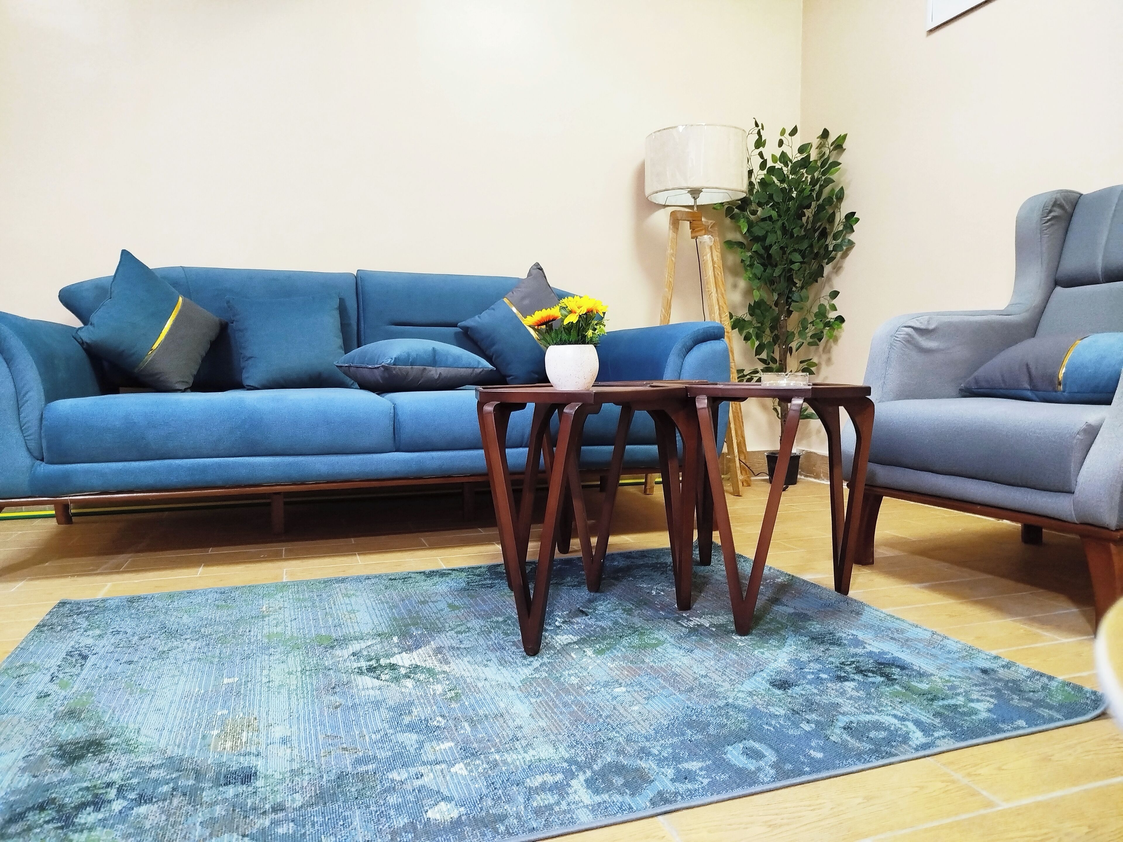 Una sala de estar con un sofá azul, una mesa de centro de madera y un sillón azul.