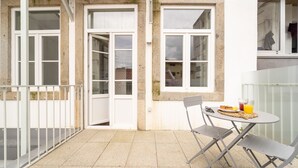 Un pequeño patio al aire libre con una mesa, sillas, una puerta blanca y una ventana.