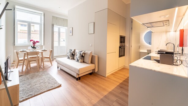 Un apartamento moderno con zona de comedor, sofá, cocina y vistas al exterior.