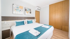 Una habitación de hotel moderna con una cama grande, un armario de madera y dos obras de arte colgadas en la pared.