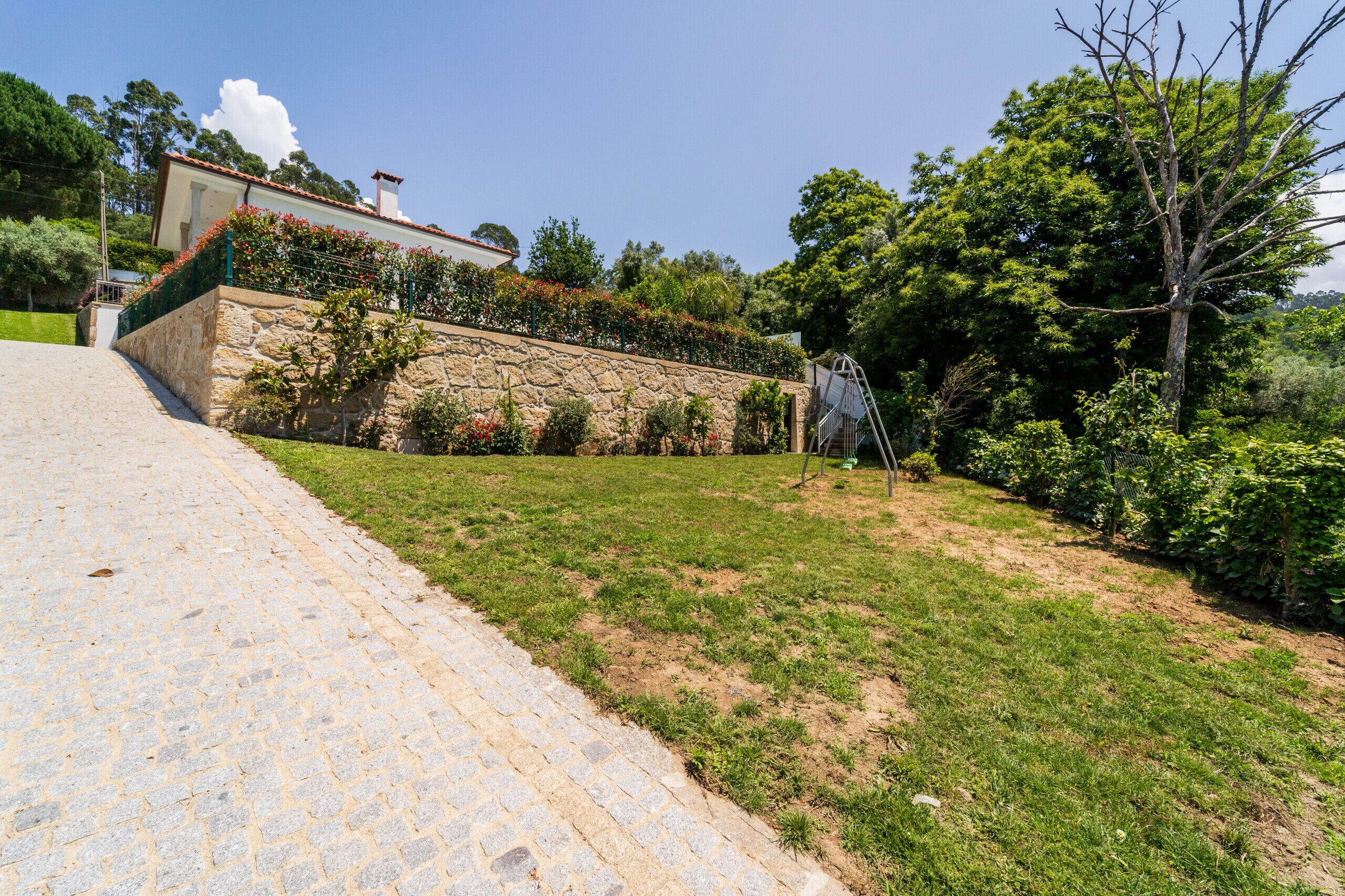 Un mur de pierre, avec un jardin et un bâtiment en arrière-plan.