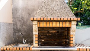 An outdoor brick oven with a metal shelf and a sink.