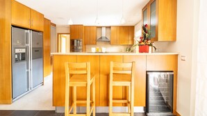 A modern kitchen with wooden cabinets, stainless steel appliances, and a central island with bar stools.