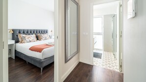 Ein Schlafzimmer mit einem großen Bett, einem Nachttisch, einem Spiegel und einer Tür zu einem Badezimmer.