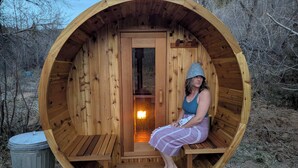 Een houten sauna met een bankje, een deur en een klein raam.
