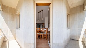 Ein Flur, der in einen Essbereich mit einem Holztisch und Stühlen führt, mit Blick in einen Raum, der von einer Deckenleuchte erhellt wird.