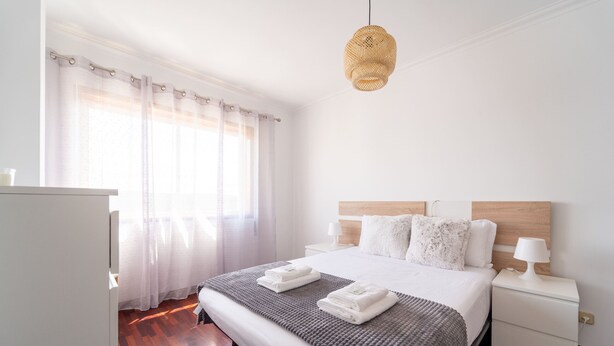 Ein ordentlich eingerichtetes Schlafzimmer mit einem großen Bett, Nachttischen und einer Hängelampe.