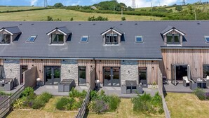 Un bâtiment moderne doté d’un toit plat, de grandes fenêtres et d’un espace extérieur couvert aménagé avec des sièges.