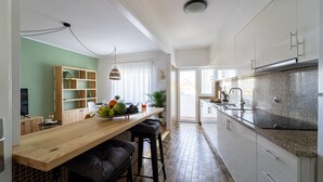 Una cocina moderna con barra de madera, armarios blancos y salpicadero de azulejos.