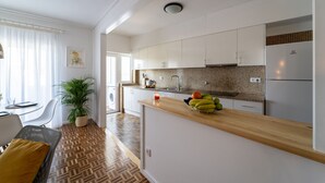 Una cocina moderna con armarios blancos, encimera de madera y un frutero.