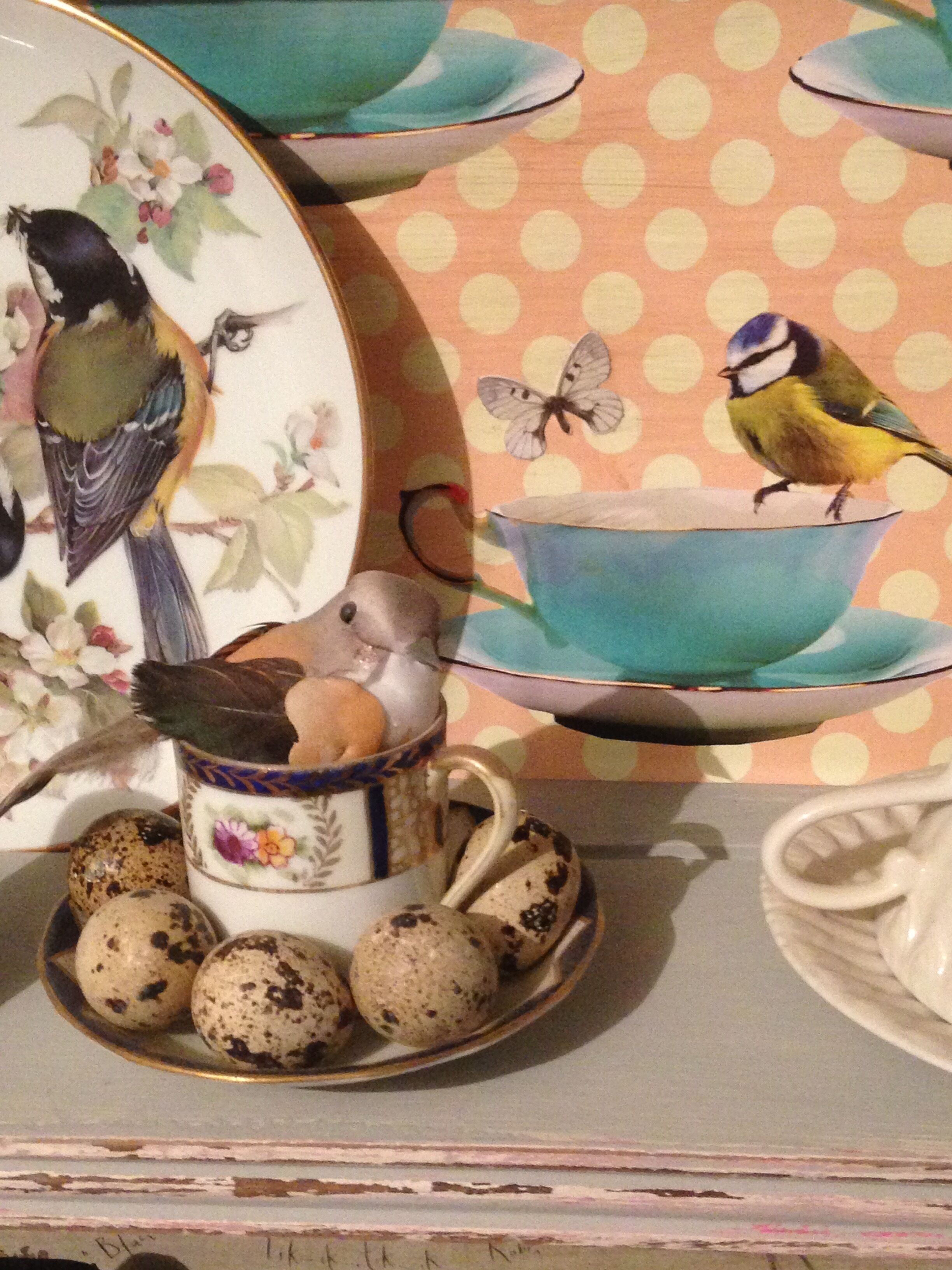 Esposizione decorativa con uccelli in ceramica, una tazza e uova di quaglia.
