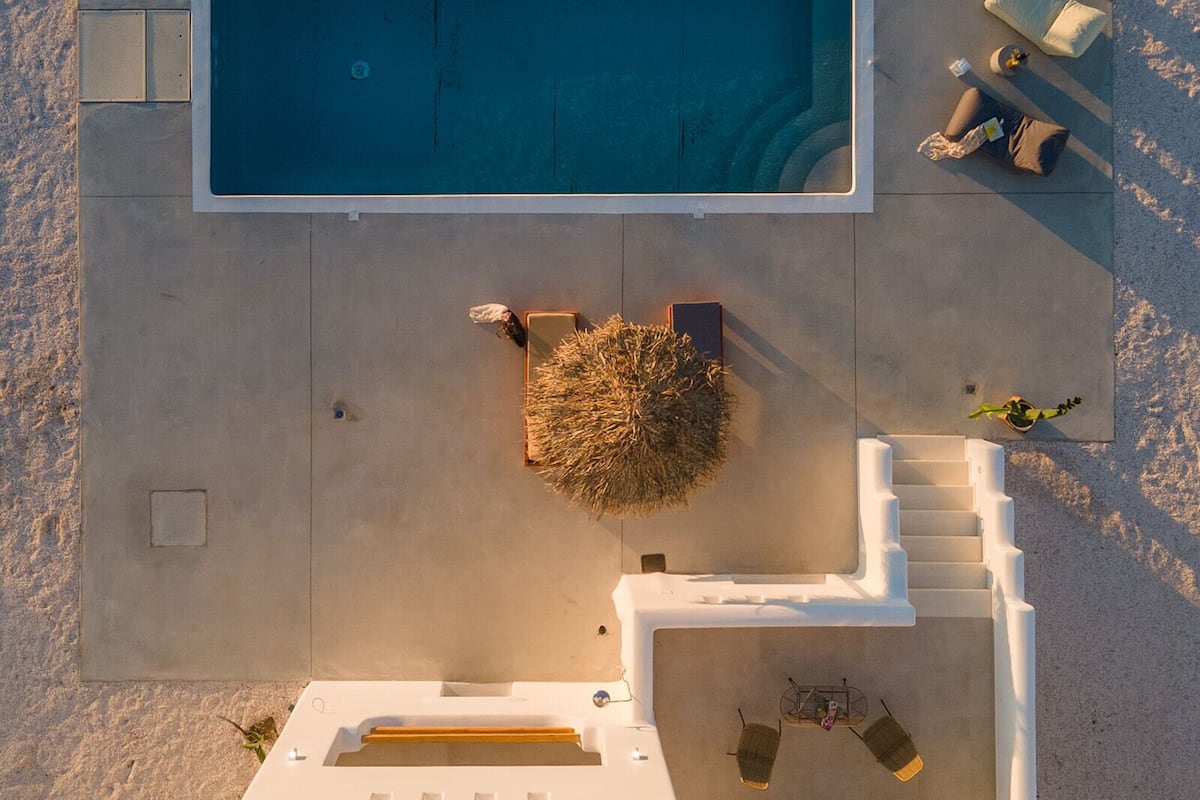 An aerial view of a swimming pool with adjacent lounge chairs and a small garden area.