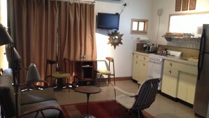 Un espacio habitable compacto con comedor, cocina y televisor montado en la pared.
