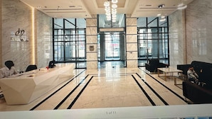 Un hall d’hôtel moderne doté d’un comptoir d’accueil, d’un espace salon et de grandes fenêtres.