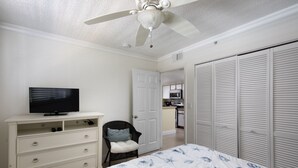 A bedroom with a bed, dresser, television, chair, and closet. - Sunrise 307-2BR/2BA condo near beaches with pool, parking, balcony (Key West)