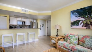 A compact living space with a kitchenette, a sofa, and a dining area. - Sunrise 307-2BR/2BA condo near beaches with pool, parking, balcony (Key West)