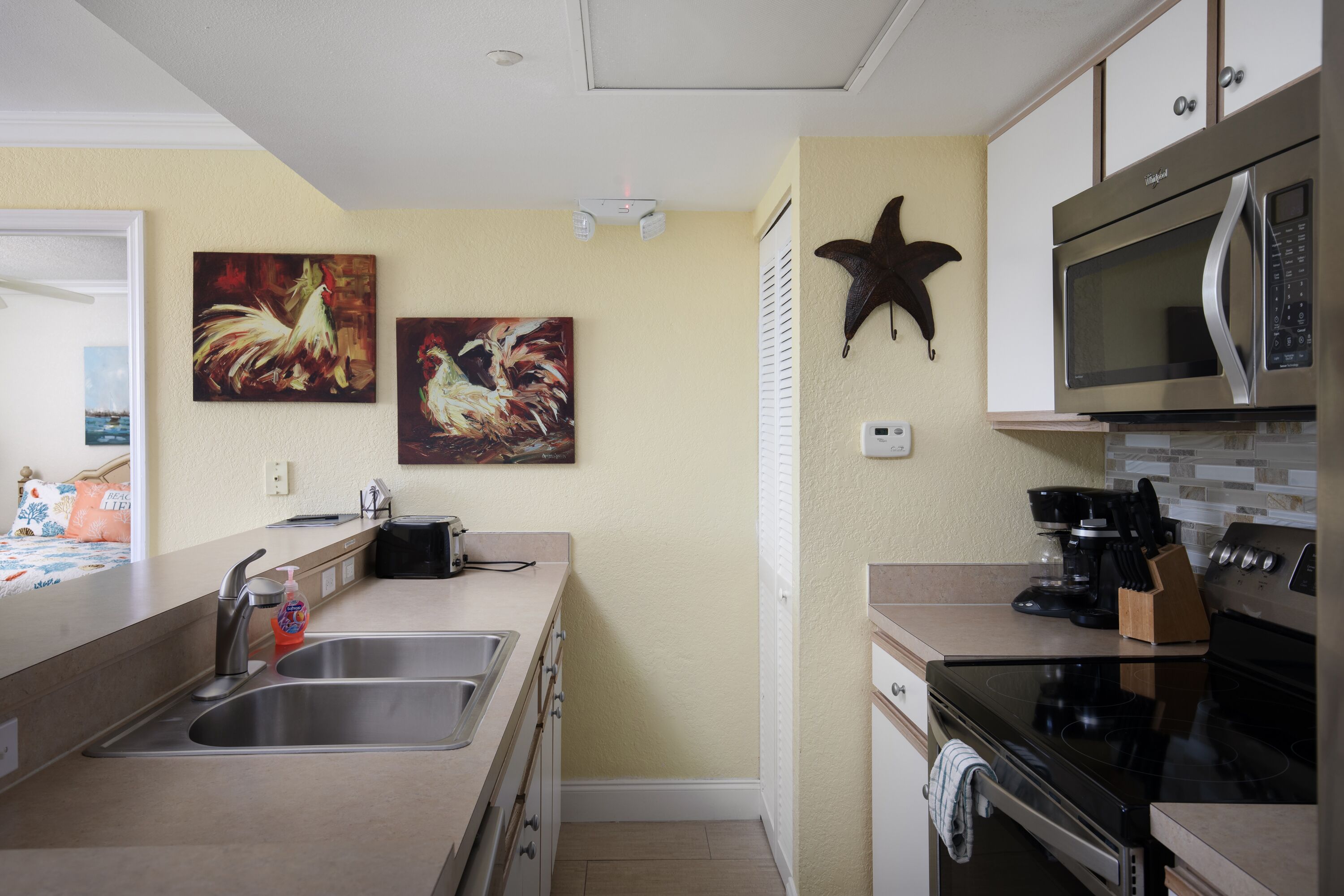 A modern kitchen with stainless steel appliances, a double sink, and decorative wall art.
