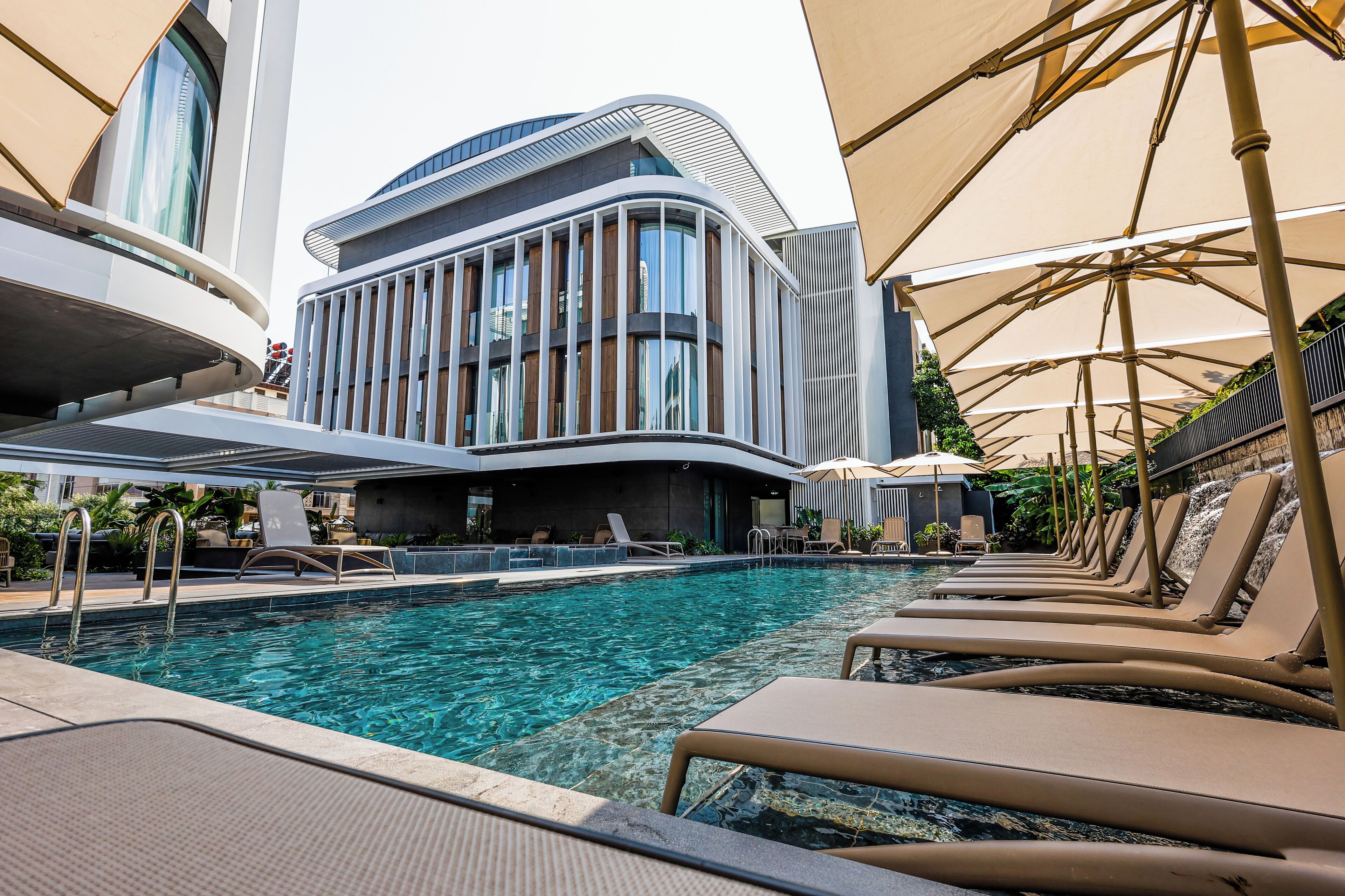Una piscina al aire libre, sombrillas, sillones reclinables de piscina