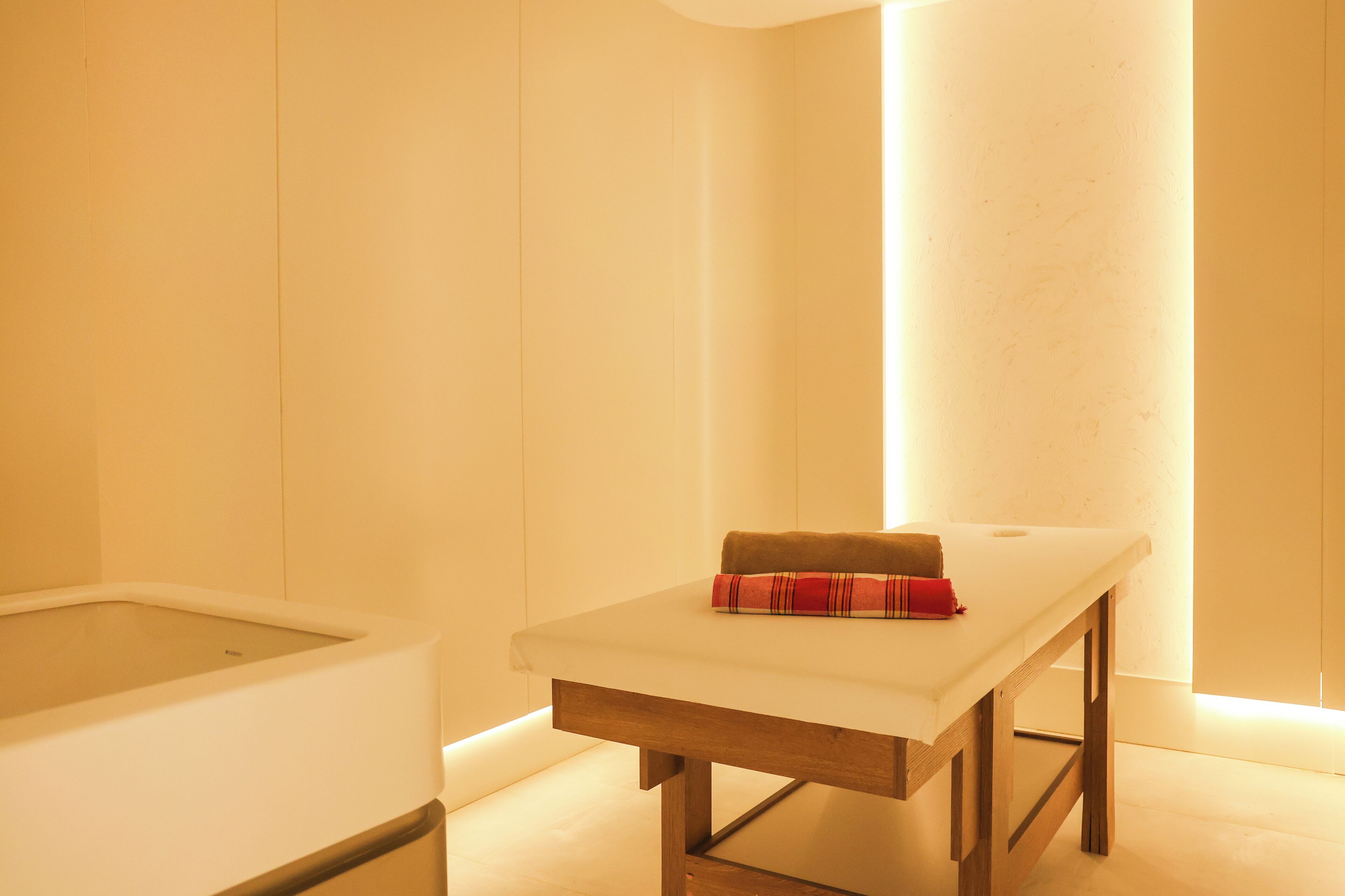 Une salle de spa équipée d’une table de massage, d’une baignoire et de serviettes.
