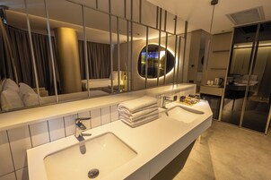 Un baño de hotel moderno con un espejo grande, dos lavamanos y un perchero para toallas.