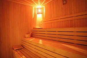 Una sauna de madera con bancos y una lámpara fijada en la pared.