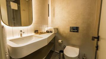 A modern bathroom with a large sink, mirror, toilet, and shower.