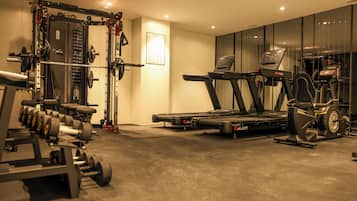 Een fitnessruimte met gewichthefapparatuur, loopbanden en spinningfietsen.