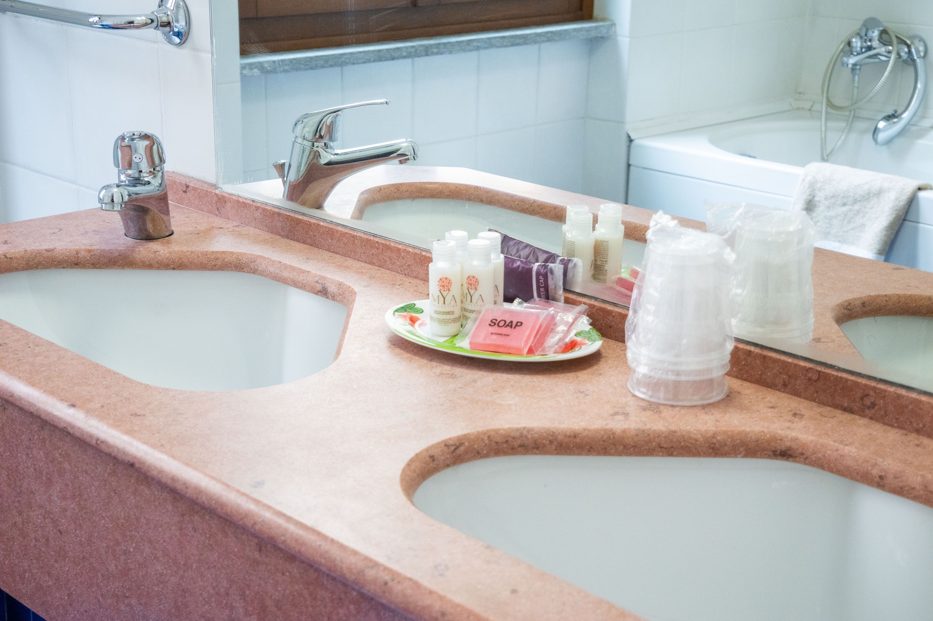 A bathroom with two sinks, a mirror, and toiletries on the countertop.