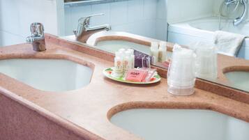 A bathroom with two sinks, a mirror, and toiletries on the countertop.