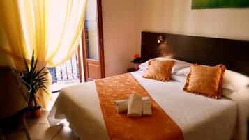 Habitación de hotel con una cama, una planta en maceta y vistas al exterior.