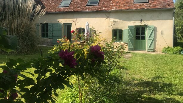 A two-story house with a tiled roof, green shutters, and a small garden with flowers. - Maison Nature Dans le Perche, à 100 m de la Forêt de Bellême (Belforêt-en-Perche)