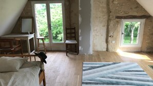 A room with a sloped ceiling, a bed, a desk, a chair, and a large window. - Maison Nature Dans le Perche, à 100 m de la Forêt de Bellême (Belforêt-en-Perche)