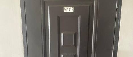 A black door with a number plate reading "1418" and a simple metal handle.