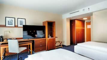 A hotel room with a bed, a desk with a chair, a television, and a wardrobe.