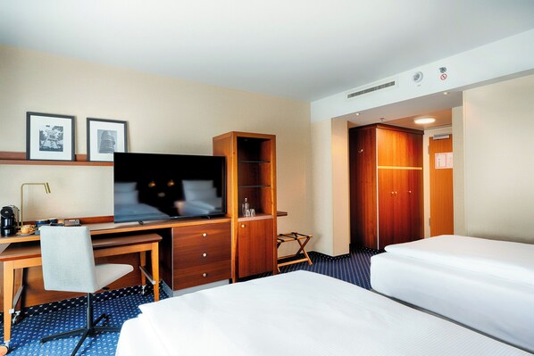 Una habitación de hotel con cama, escritorio, silla, televisor y armario.