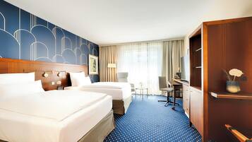 Een hotelkamer met twee bedden, een bureau, een stoel, een lamp en een kledingkast.