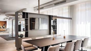 Modern meeting space with a long conference table, six chairs, and a large flat-screen TV.
