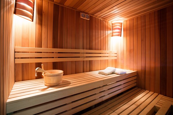Una sauna de madera con bancos y un cubo de madera.